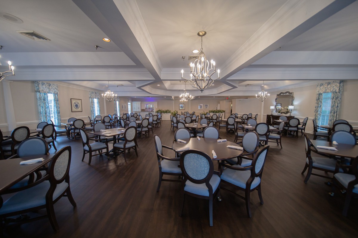 Elegant dining room with multiple tables and chandeliers.