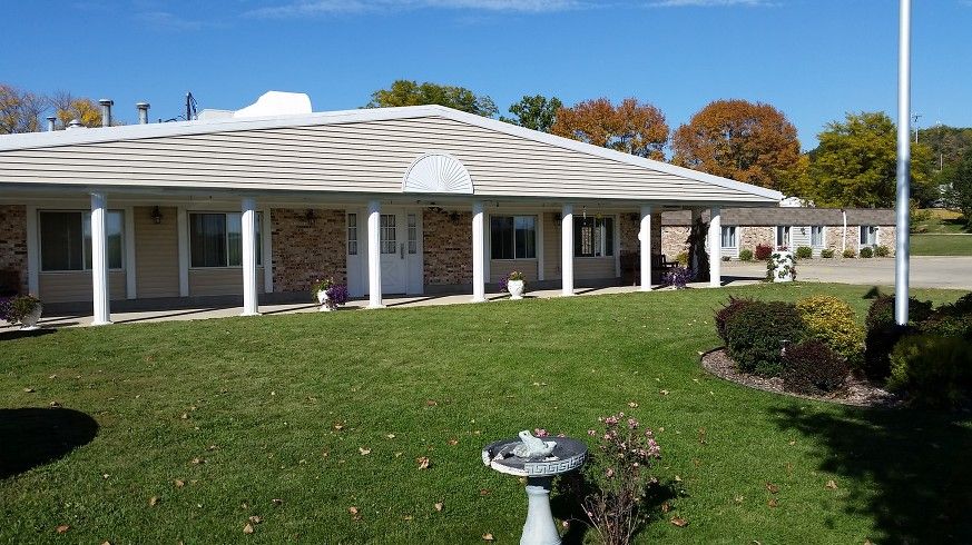 A single-story house with a front porch featuring columns and a well-maintained lawn.