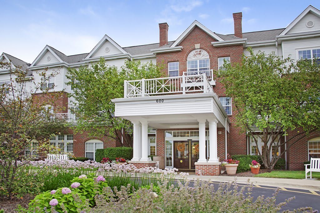 A residential building with a grand entrance, featuring white columns and surrounded by greenery.