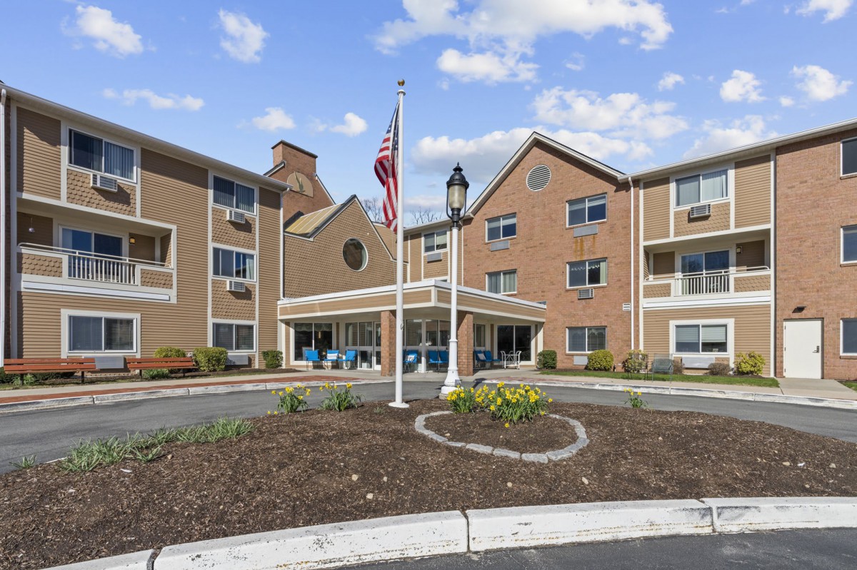 A residential building with flags at the entrance and landscaping in front.