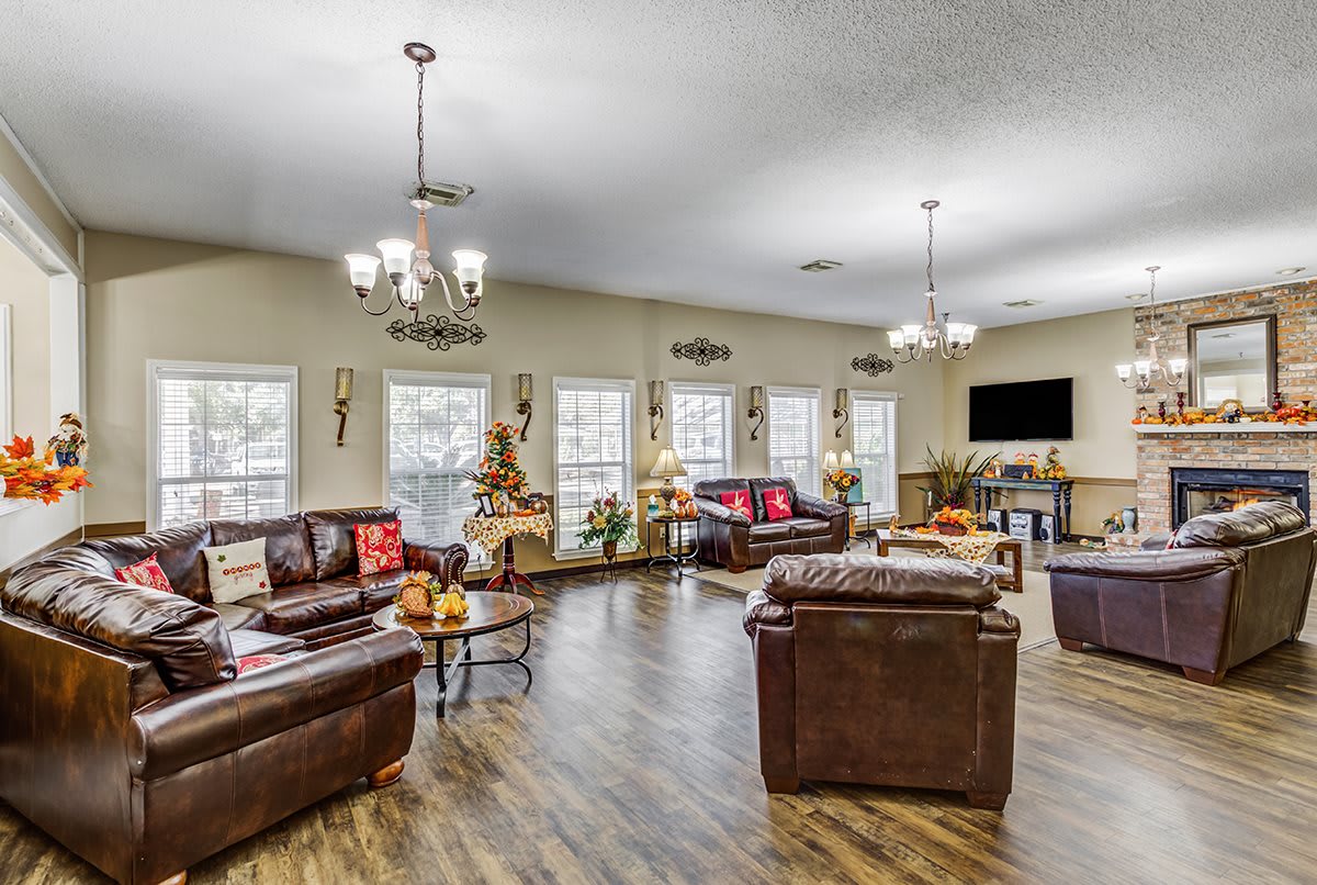 Spacious living room with elegant chandeliers, leather sofas, and large windows.
