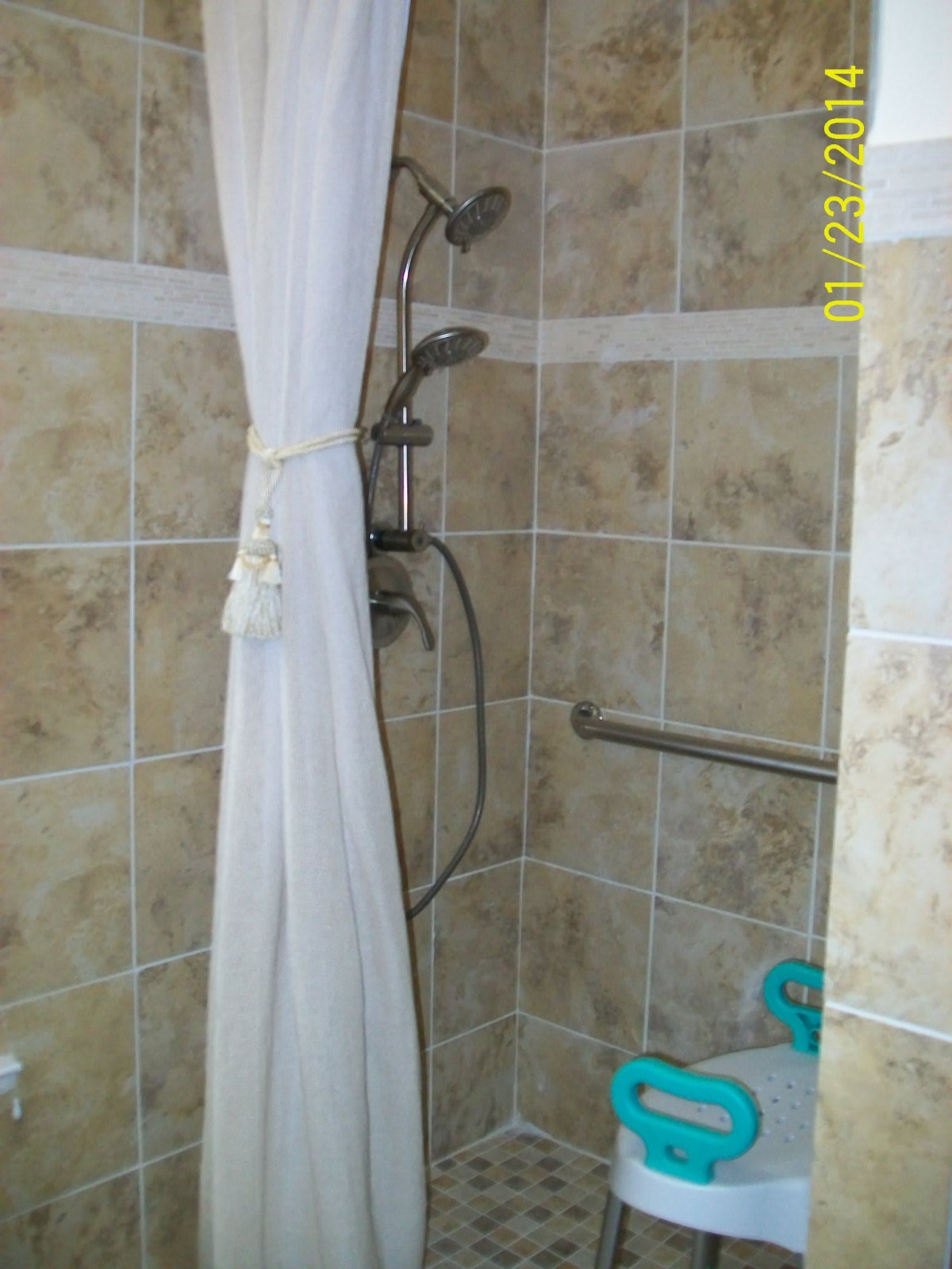 A tiled shower area with a curtain and grab bar for safety.