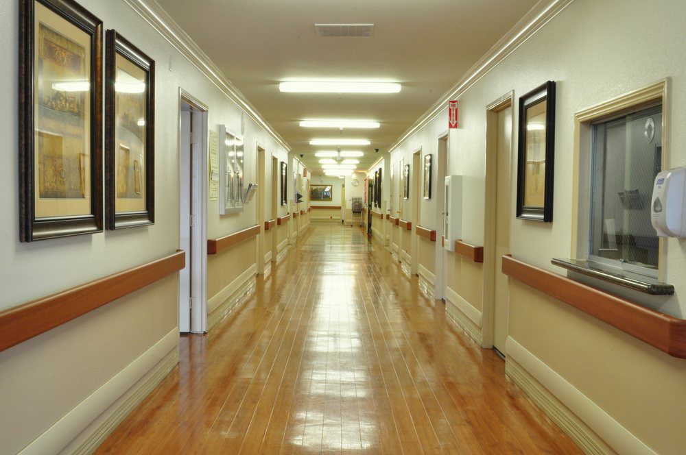 A well-lit hospital corridor with polished floors and artwork on the walls.