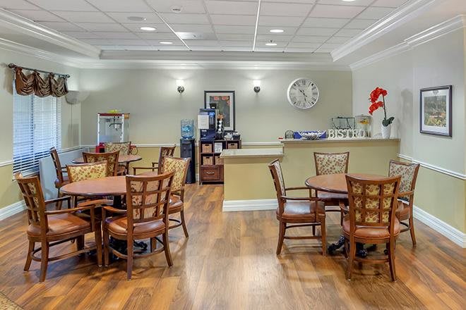 A cozy dining room with wooden tables and chairs arranged neatly on a hardwood floor.