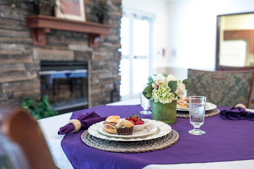 A beautifully arranged dining table with a purple tablecloth, elegant tableware, and a floral centerpiece.