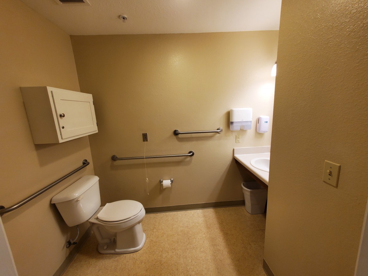 A clean, handicap-accessible bathroom with a toilet, sink, and grab bars.