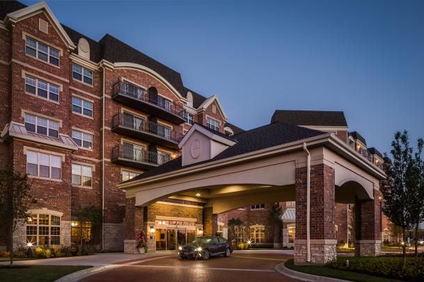 A luxurious hotel entrance with a car parked under the portico during the evening.