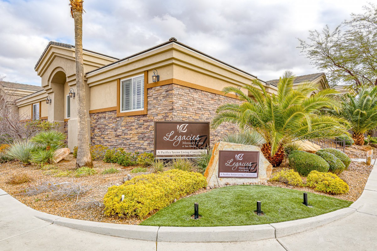 A modern residential building with stone facade and well-maintained landscaping featuring a palm tree.