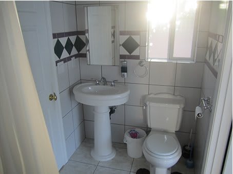 A small bathroom with a pedestal sink, toilet, and tiled walls.