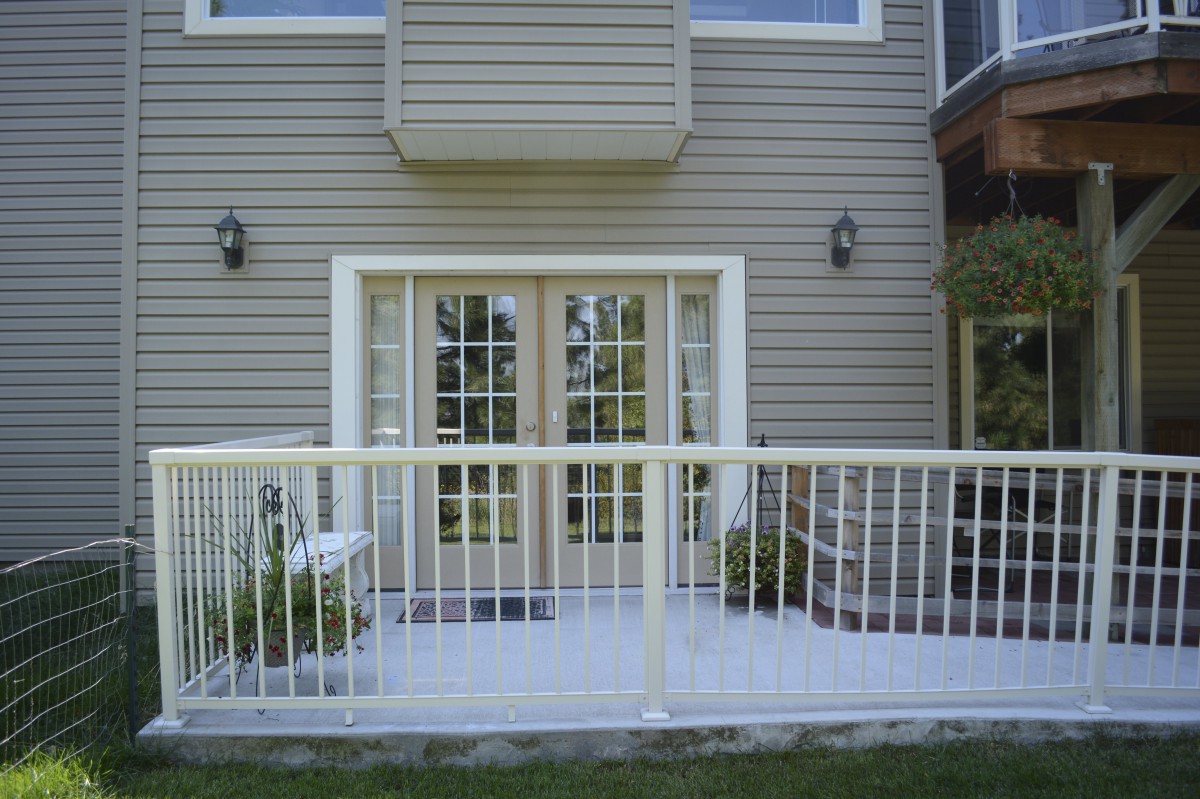 A house exterior featuring a patio with French doors and a white railing.