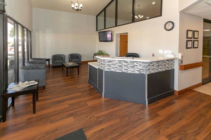 A modern office reception area with a seating arrangement and wooden flooring.