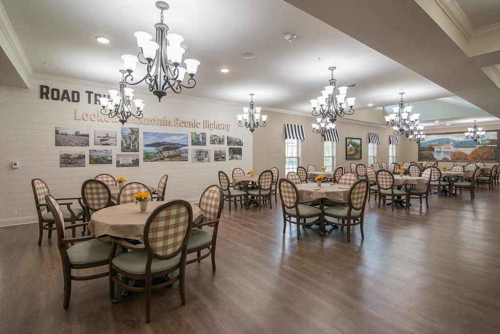 A well-lit dining area featuring elegant chandeliers and neatly arranged tables with chairs.