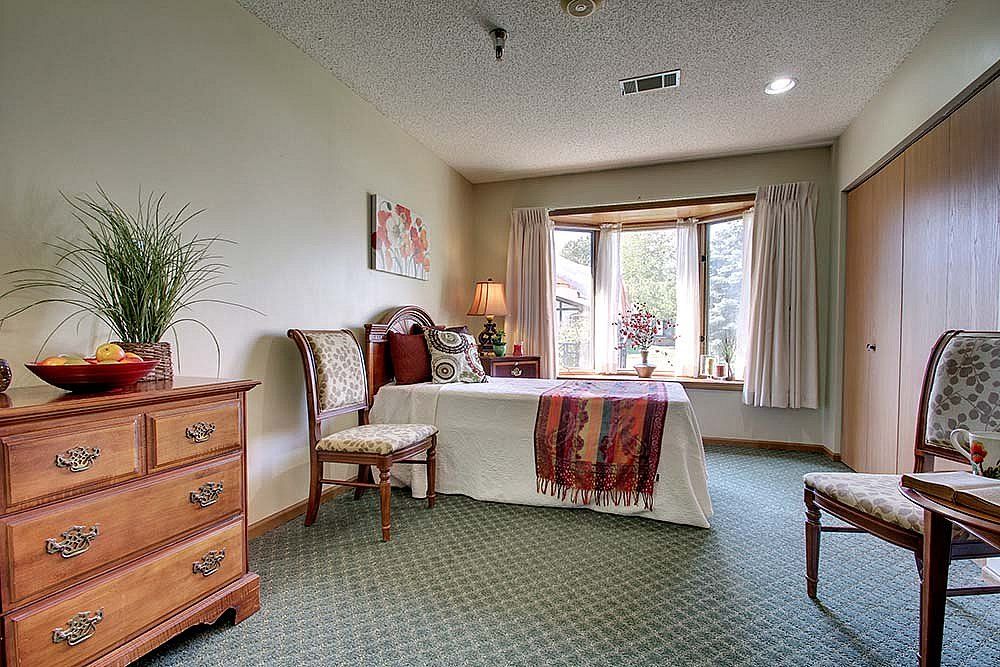 A cozy bedroom with classic furniture and a large window letting in natural light.