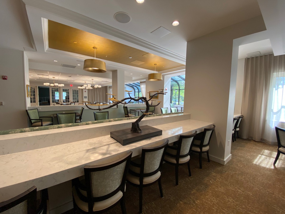 A modern dining area featuring a long counter with chairs and a decorative sculpture.