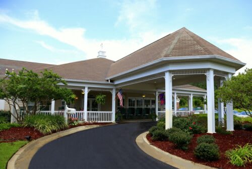 A beautifully landscaped entrance to a building with a covered driveway.