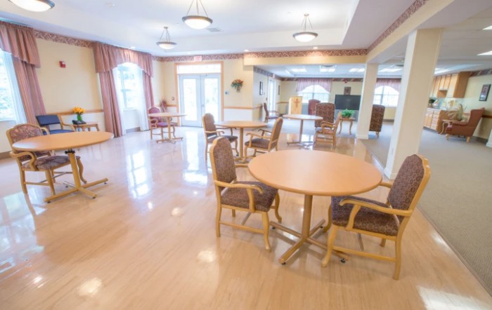 A spacious and well-lit dining area with several tables and chairs set up on a polished wooden floor.
