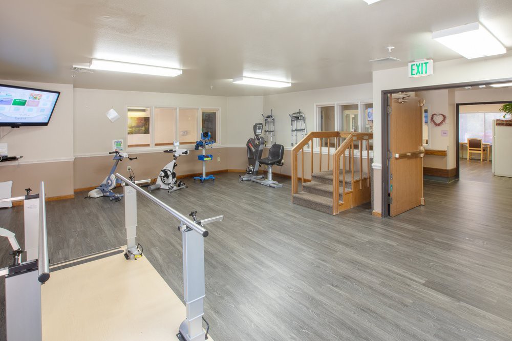 A spacious gym area equipped with exercise bikes and parallel bars for rehabilitation.
