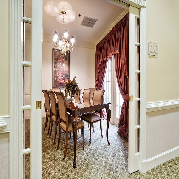 Elegant dining room with a chandelier, classic furniture, and rich drapery.