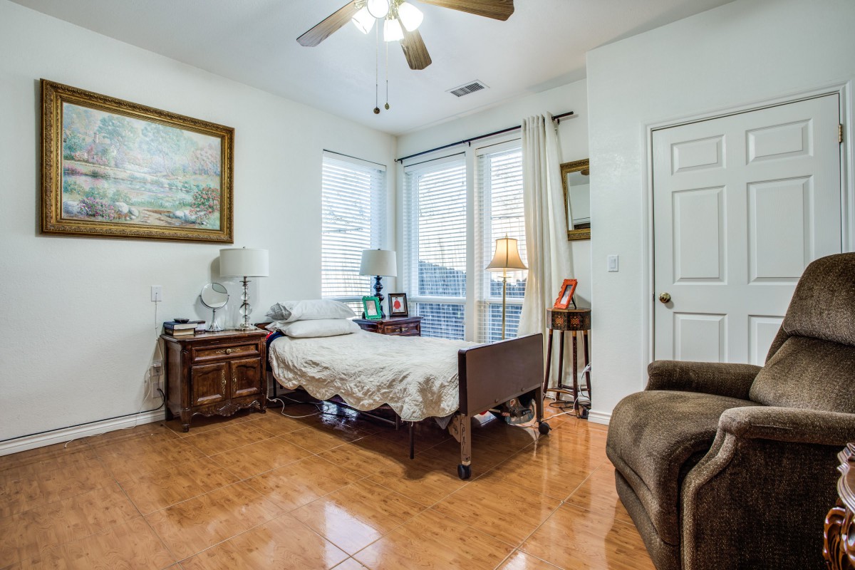 A cozy bedroom with a single bed, bedside table, and large windows allowing natural light in.