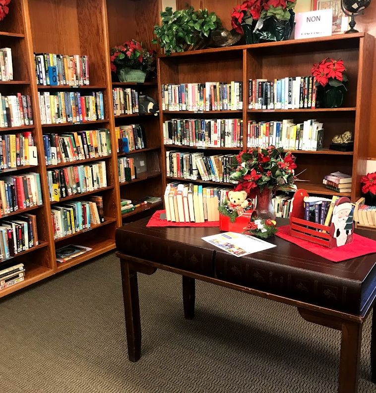 A cozy library corner with bookshelves and a table decorated for the holidays.