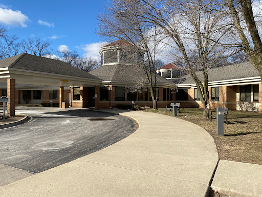A view of a serene building with a curved pathway, surrounded by trees under a clear blue sky.