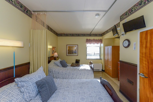 A cozy hotel room featuring two beds, warm lighting, and a view from the window.