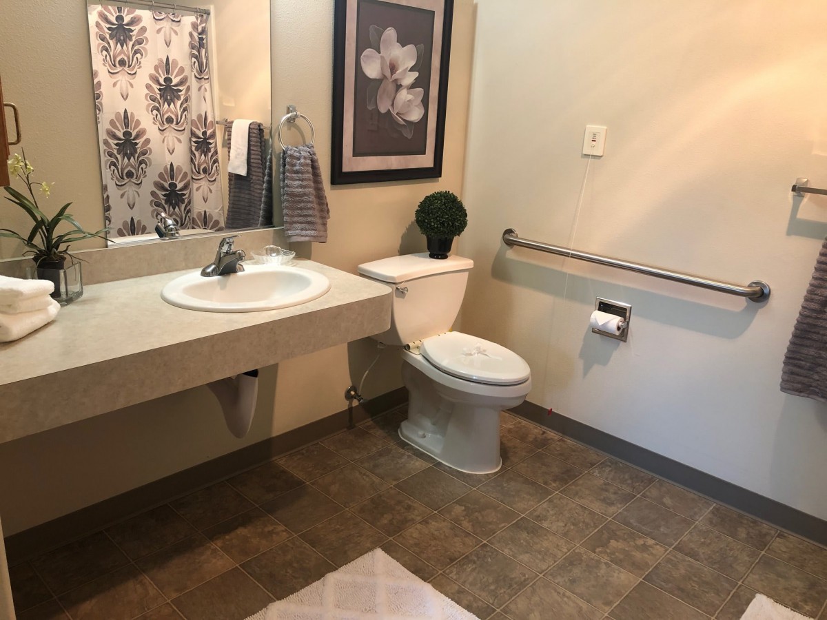 A clean and well-decorated bathroom with a sink, toilet, and wall art.
