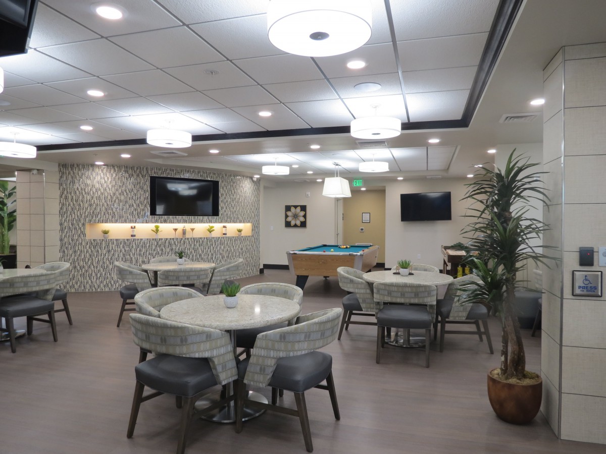 A modern lounge area with tables, chairs, a pool table, and television screens.