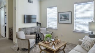 A cozy living room with armchairs, a coffee table, and a wall-mounted television.