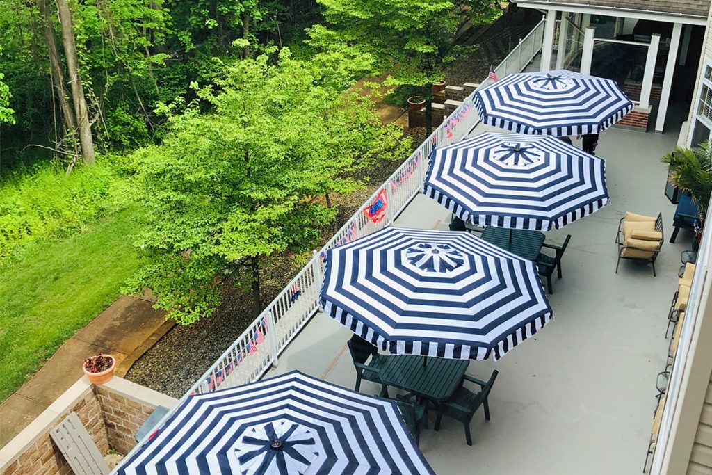 Aerial view of a patio with striped umbrellas and tables, surrounded by lush greenery.