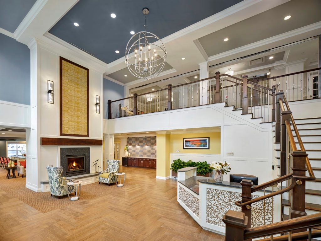 Spacious and elegant living room with a modern design, featuring a striking chandelier, cozy fireplace, and grand staircase.