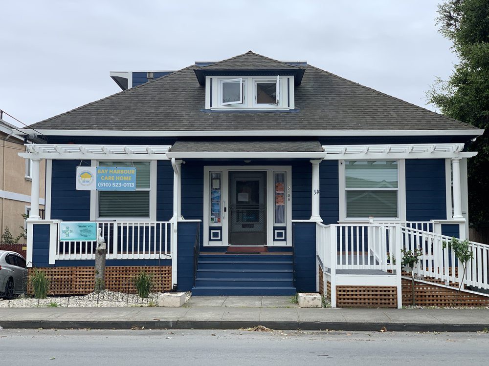 A blue residential house with a front porch and multiple windows.