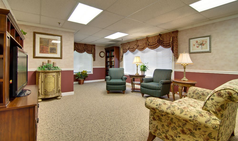 A cozy living room with traditional decor featuring armchairs, a carpet, and warm lighting.