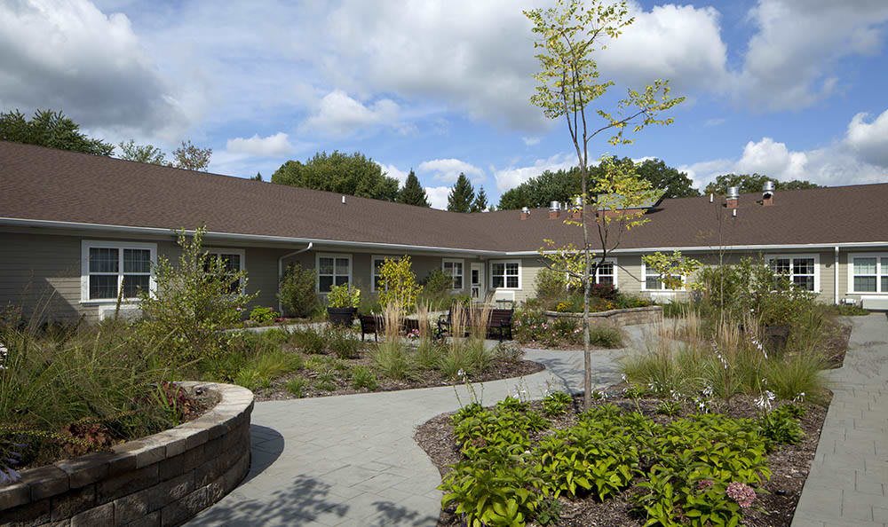 A well-maintained garden with a pathway leading to a building under a partly cloudy sky.