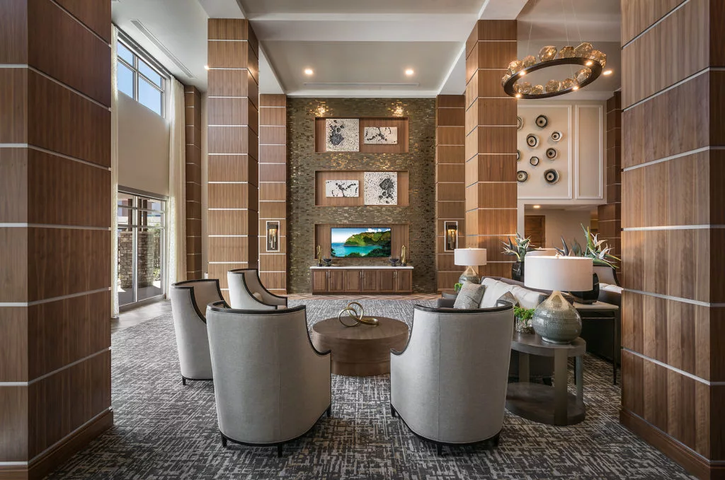 A modern and luxurious lobby featuring a seating area with elegant chairs, a television, and stylish artwork.