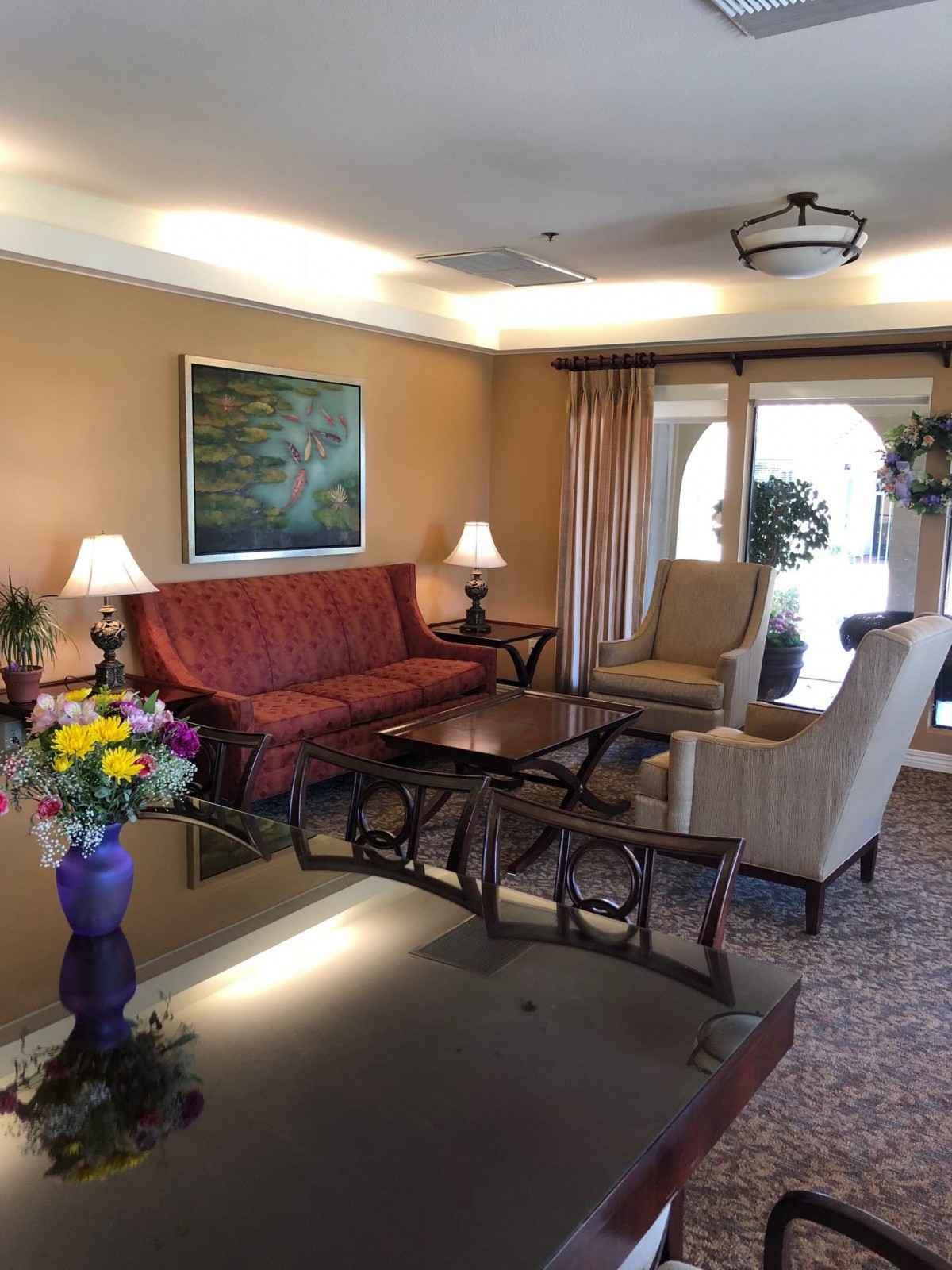 A cozy living room with a red sofa, comfortable armchairs, and decorative elements like lamps and artwork.