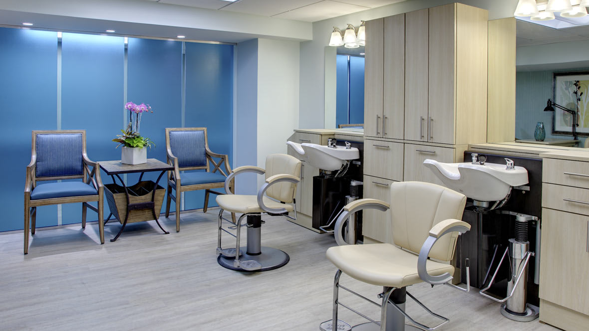 A modern hair salon interior with styling chairs, mirrors, and cabinetry.