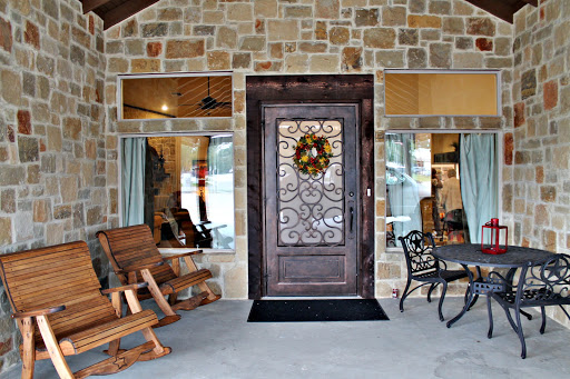A welcoming entrance featuring a beautifully designed door with a decorative wreath, surrounded by a stone exterior and inviting porch seating.