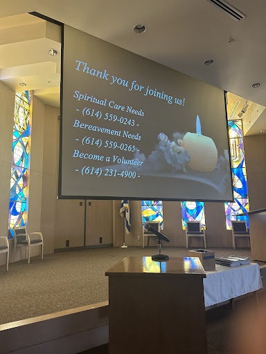 A thank you message displayed on a screen inside a church, featuring colorful stained glass windows.