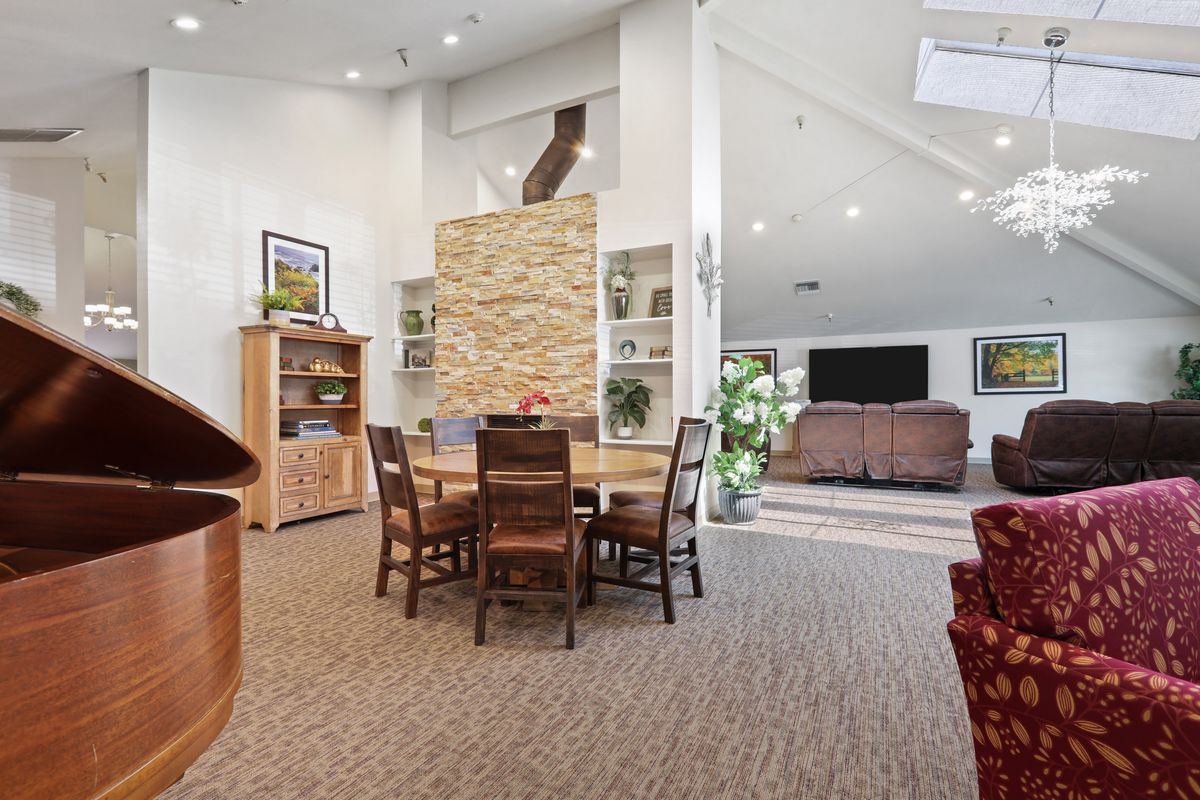 A spacious and modern living area featuring a dining set, high ceilings, and cozy furniture.