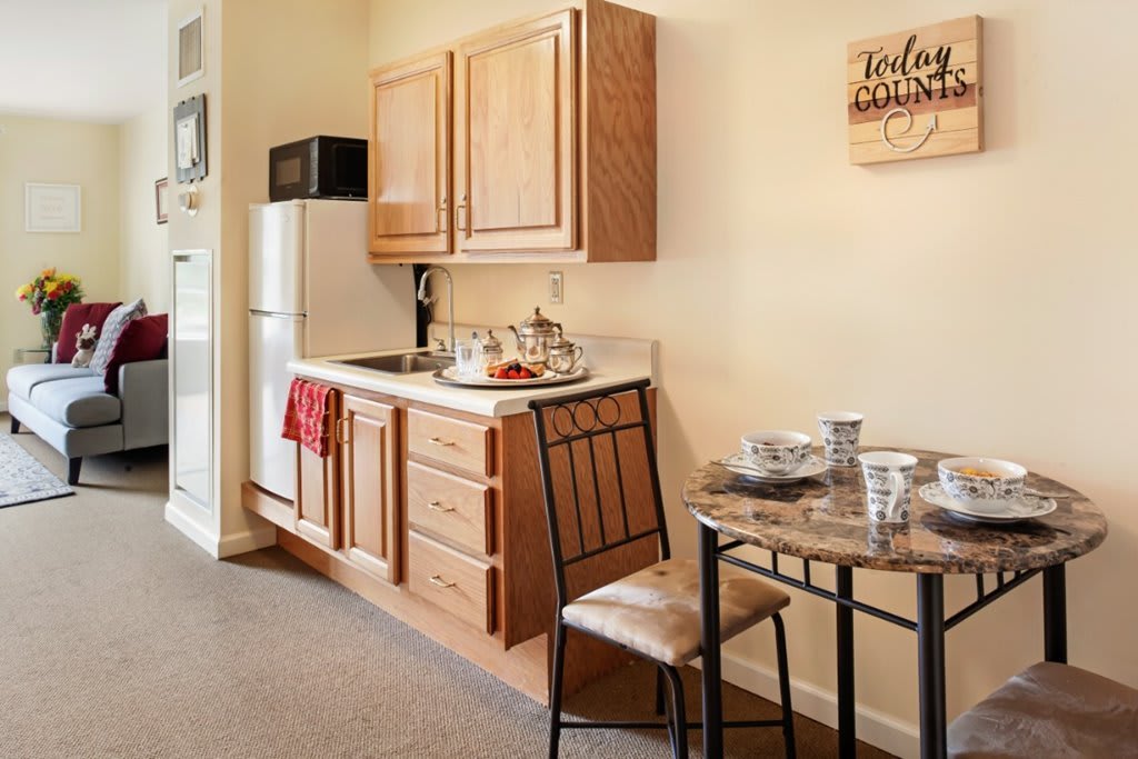 A cozy apartment kitchen with wooden cabinets, a small dining table, and essential appliances.