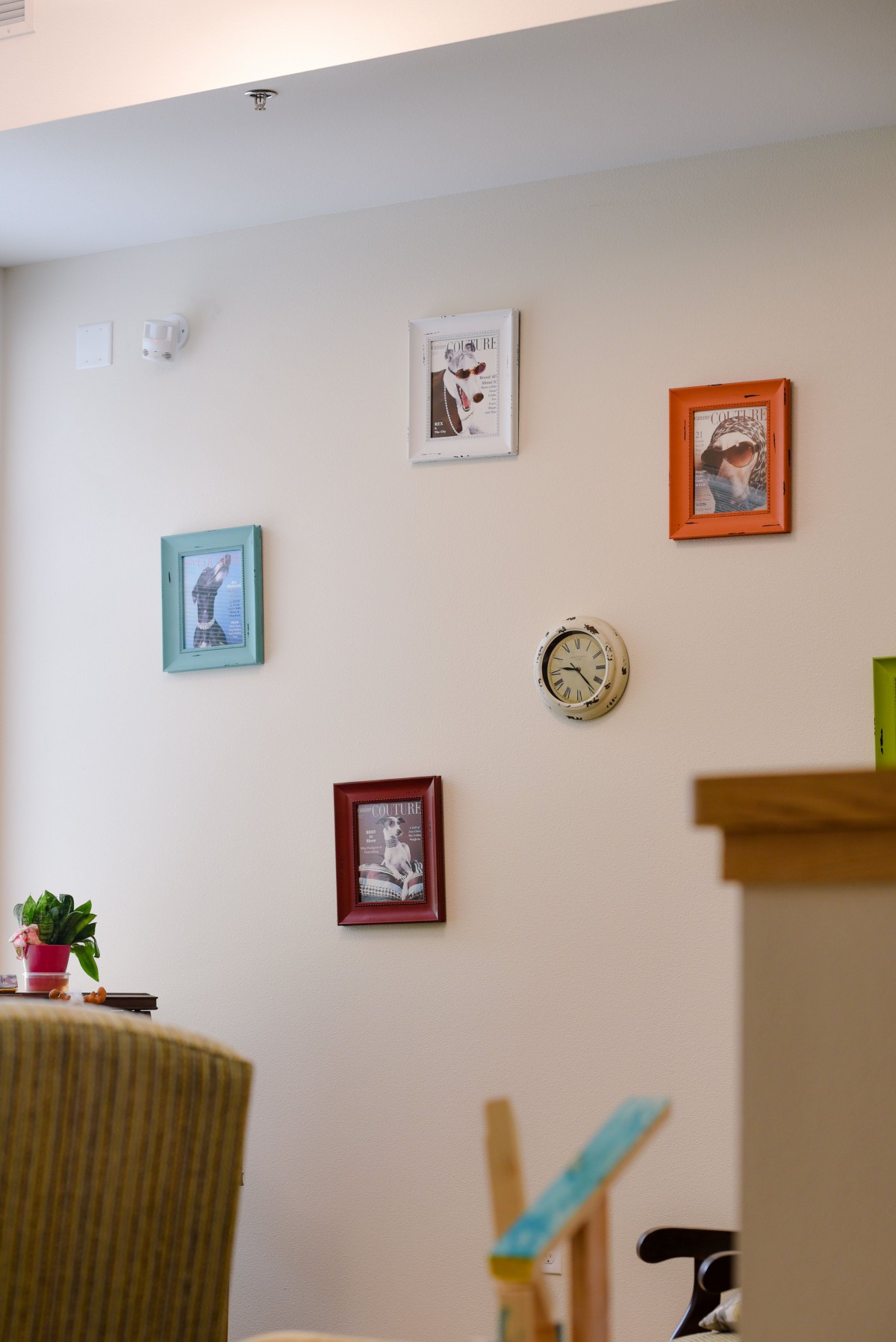 A cozy interior wall decorated with colorful frames and a small clock.