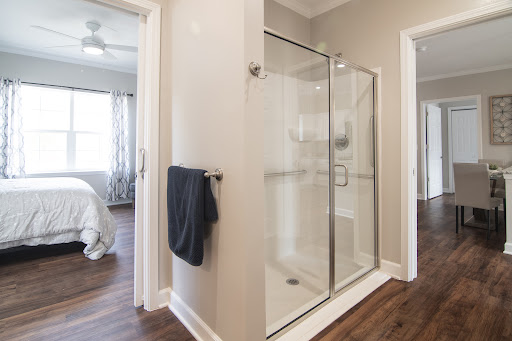 A stylish modern bathroom featuring a glass shower, towel rack, and warm wood flooring.