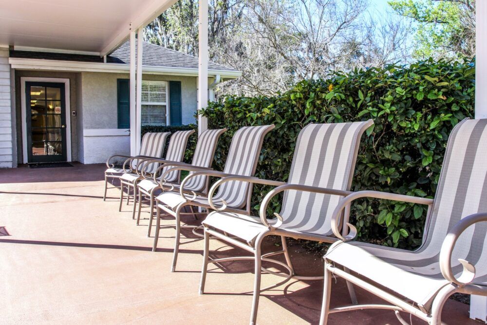 A row of outdoor patio chairs lined up on a porch.
