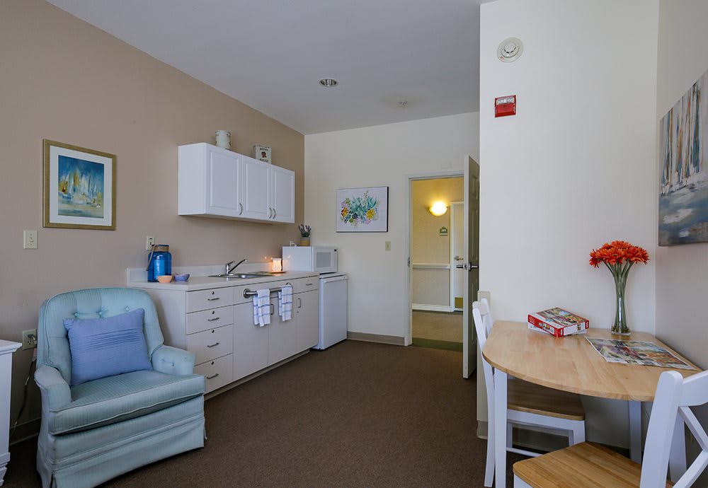 A cozy living area with a small kitchenette, featuring a sofa, table, and chairs.