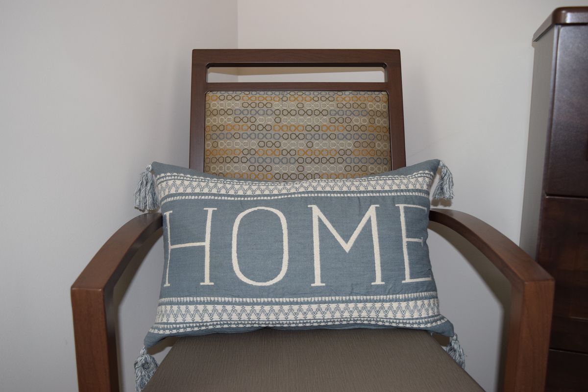 A decorative pillow with the word 'HOME' placed on a chair.