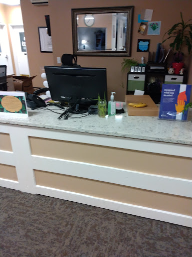 A view of a reception desk in an office setting, featuring a computer and various informational materials.