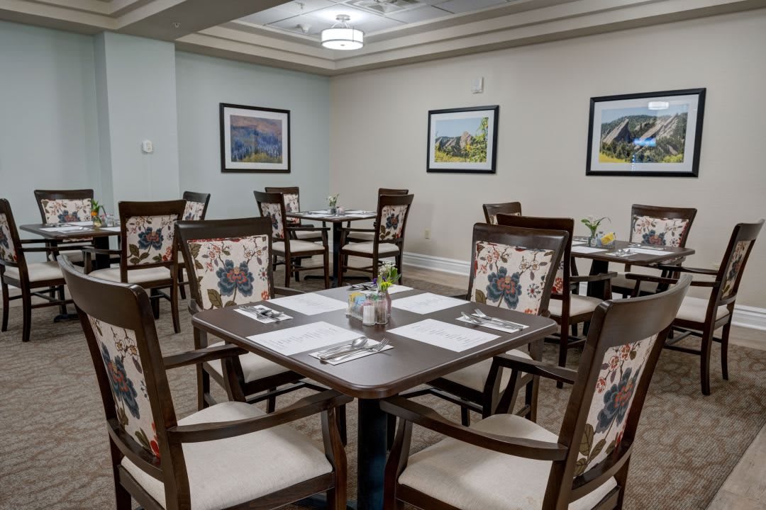 A neatly arranged restaurant dining area with tables and chairs, complemented by wall art.