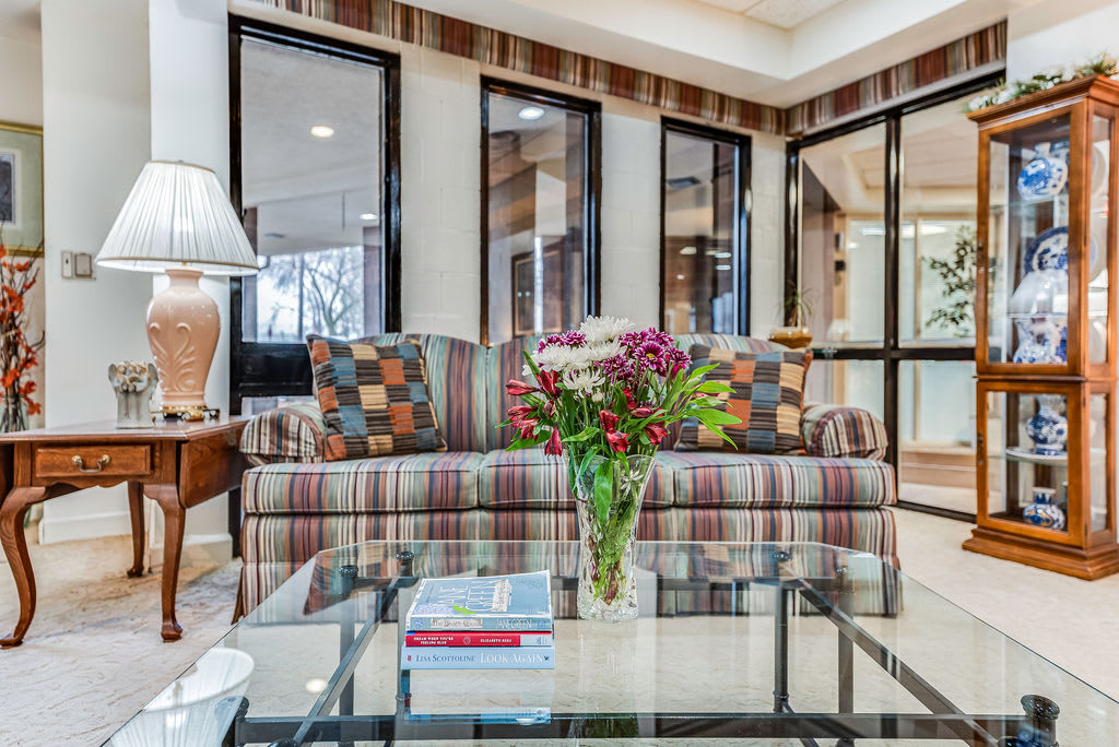 A modern living room with a patterned sofa and a glass table adorned with fresh flowers.
