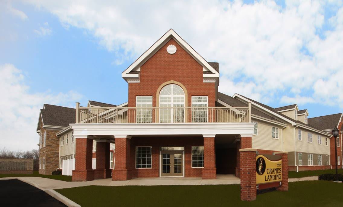 A brick building with a prominent entrance and large windows, featuring a sign indicating it's a library.
